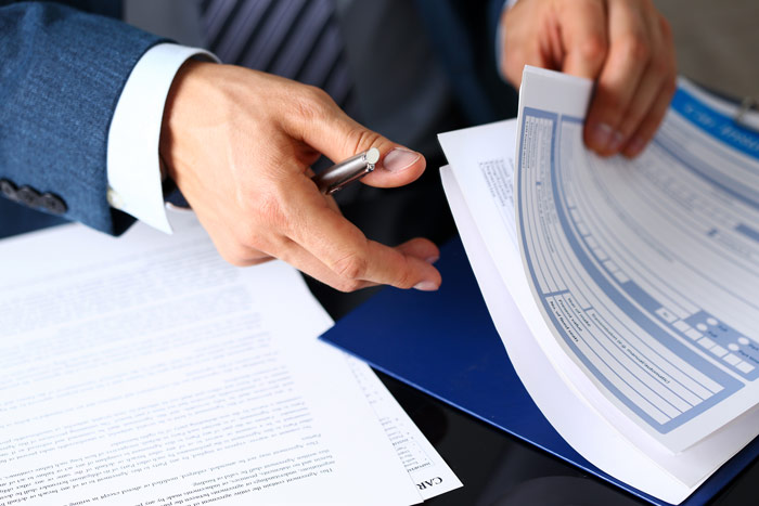 business man flipping through paperwork with a pen in hand